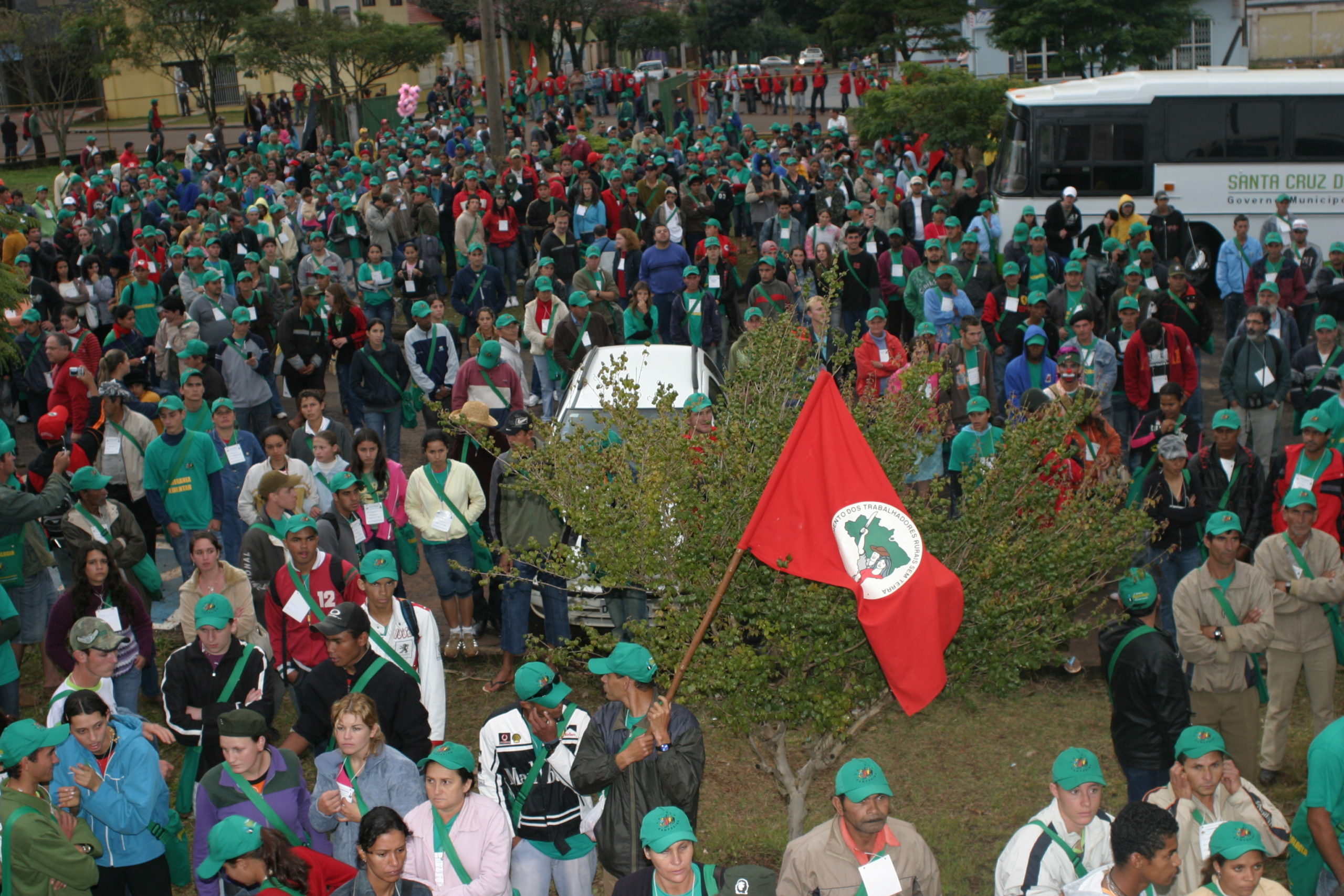 bandeira do mst erguida e centenas de pessoas reunidas