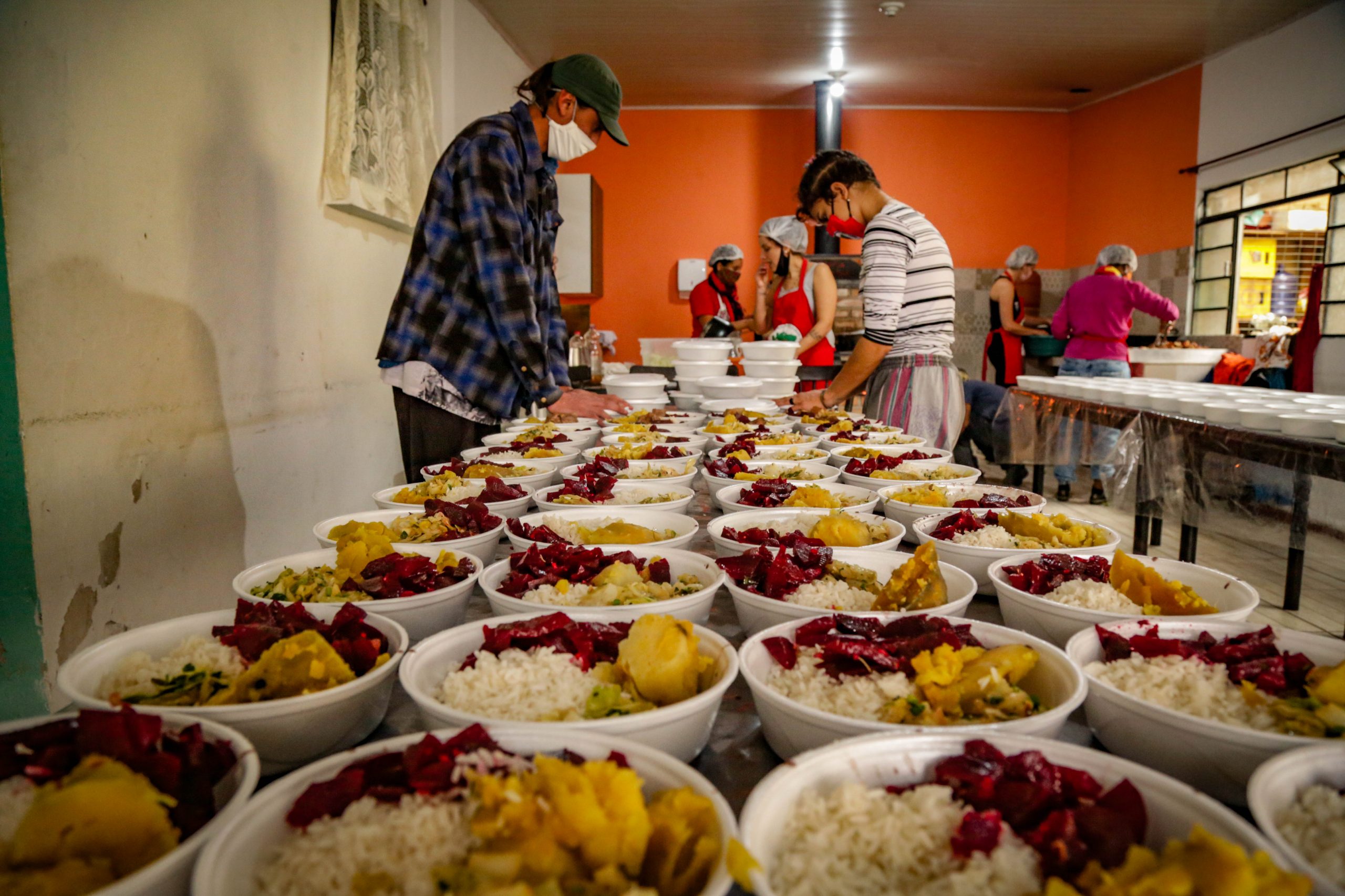 fotografia colorida mostra marmitas de comida saudável sendo preparadas para doação